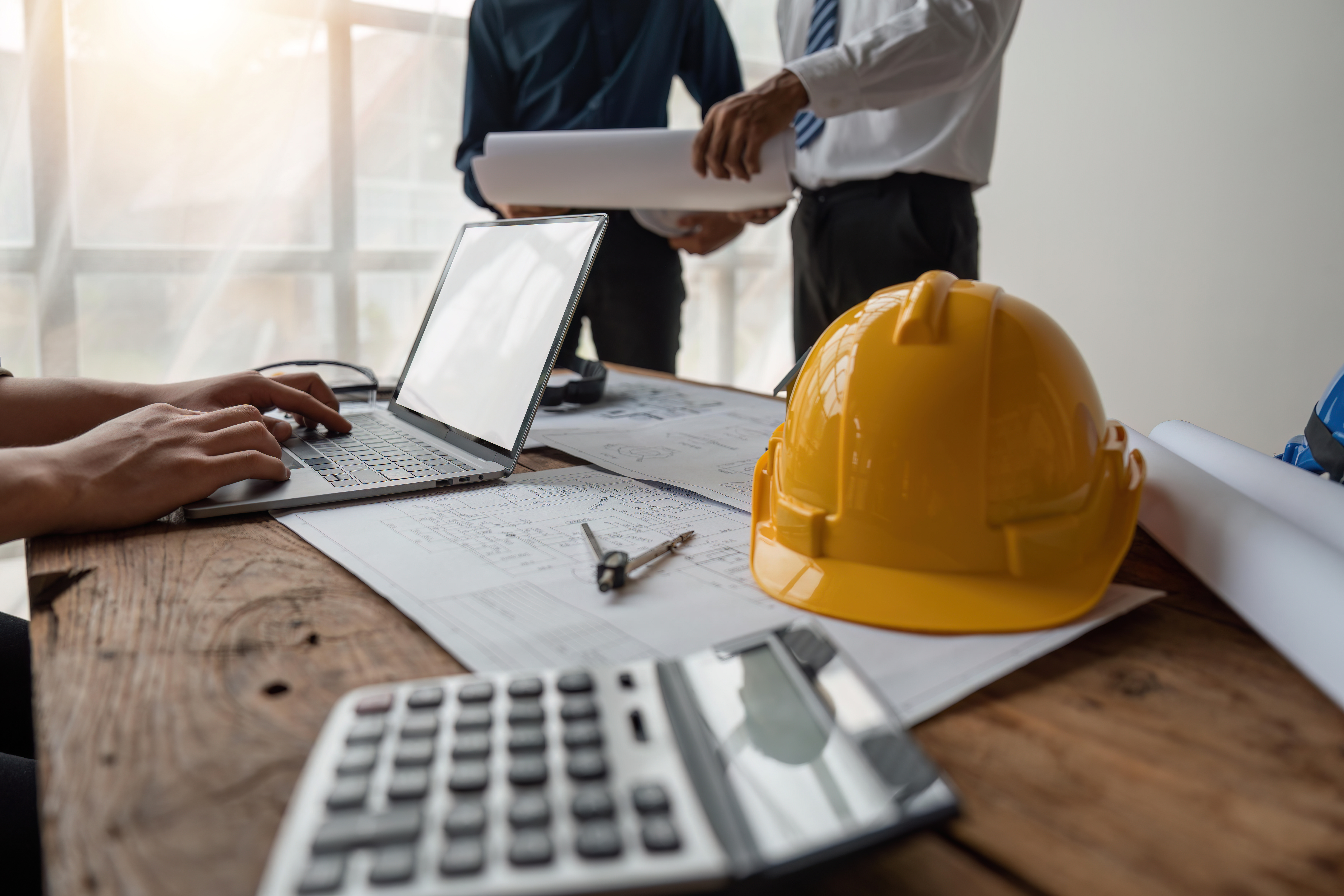 Team of engineers meeting to report project construction on laptop screen